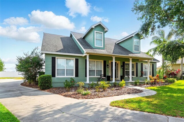 1935 Austin Ter, Winter Haven, FL 33884 - cape cod house featuring covered porch, roof with shingles, and a front lawn