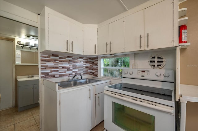 kitchen featuring tasteful backsplash, white electric range oven, sink, and white cabinets