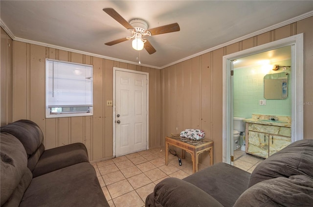 tiled living room with ornamental molding, wooden walls, and ceiling fan