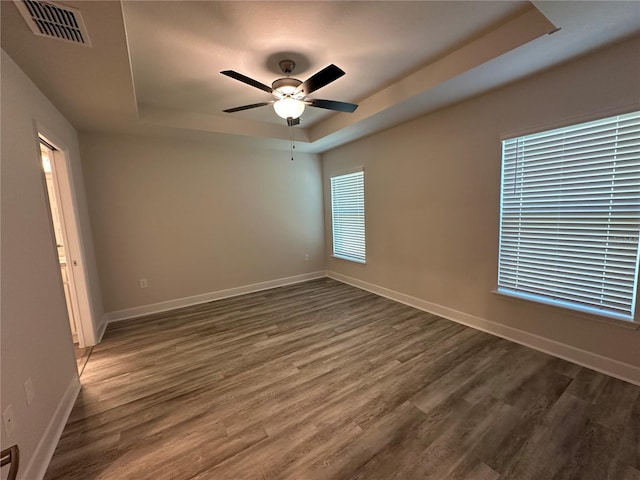 unfurnished room featuring dark hardwood / wood-style flooring, a raised ceiling, and ceiling fan