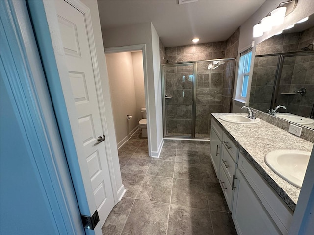 bathroom featuring tile patterned flooring, vanity, toilet, and a shower with shower door