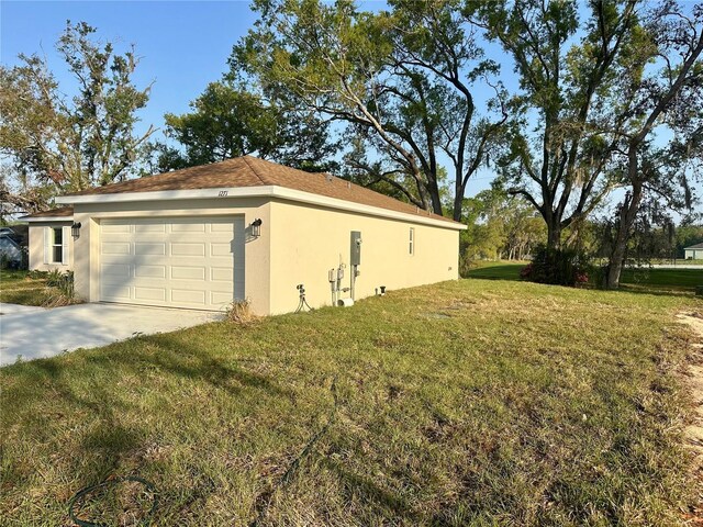 view of side of home with driveway, a lawn, an attached garage, and stucco siding