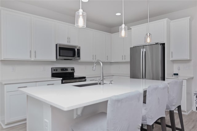 kitchen with white cabinets, a center island with sink, appliances with stainless steel finishes, and sink