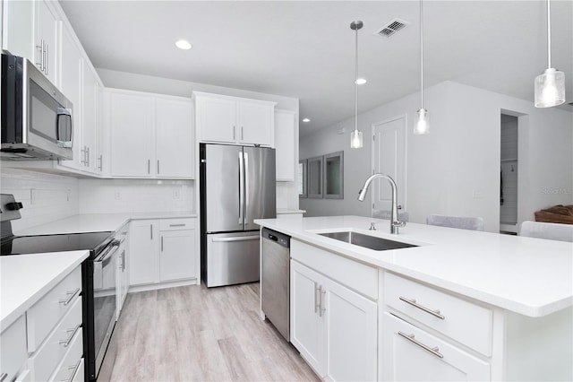 kitchen with white cabinets, stainless steel appliances, sink, and an island with sink