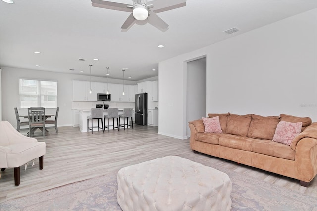 living room with light hardwood / wood-style floors and ceiling fan