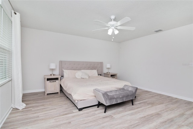 bedroom with light hardwood / wood-style floors, ceiling fan, and a textured ceiling