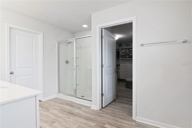 bathroom with hardwood / wood-style flooring, vanity, an enclosed shower, and a textured ceiling