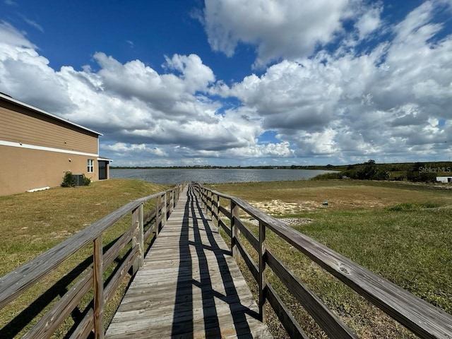 view of dock with a water view and a lawn