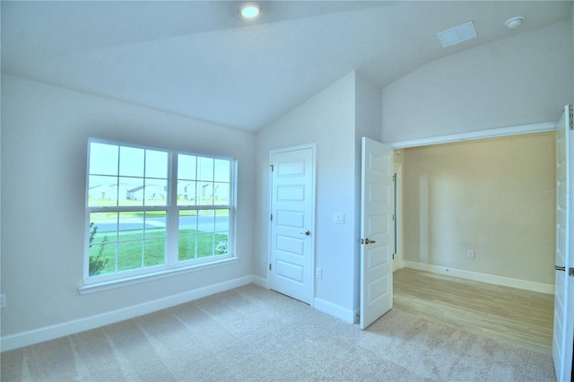 unfurnished bedroom featuring light colored carpet, vaulted ceiling, and a closet