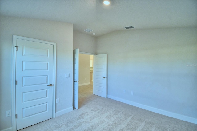 unfurnished bedroom featuring light colored carpet and lofted ceiling