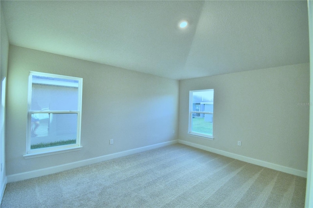 carpeted spare room with vaulted ceiling