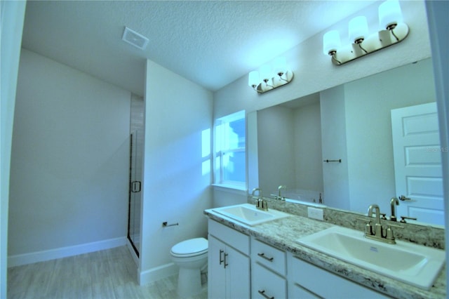 bathroom featuring wood-type flooring, toilet, a shower with door, a textured ceiling, and vanity