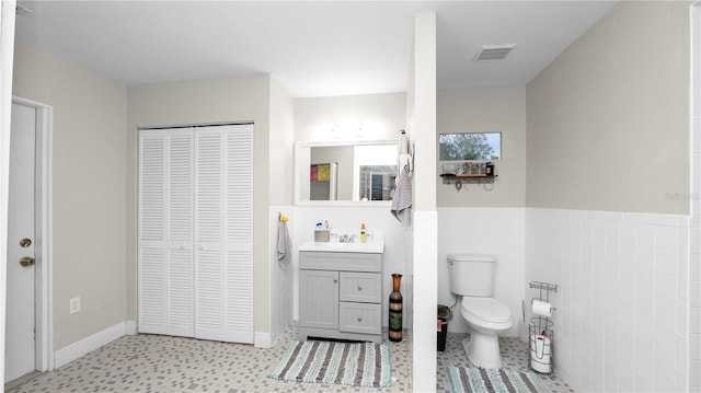 bathroom with vanity, toilet, and tile walls