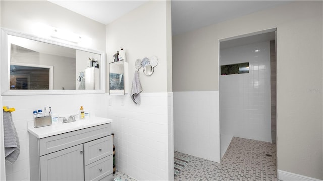 bathroom with tile walls, tiled shower, and vanity