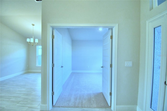 hallway with a chandelier and light colored carpet