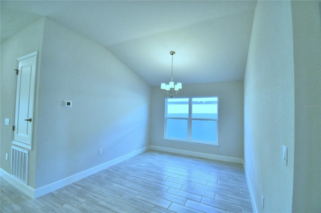 spare room featuring light hardwood / wood-style floors, vaulted ceiling, and a notable chandelier