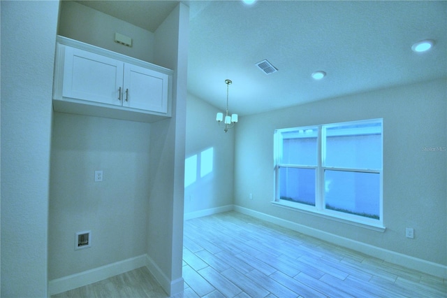 unfurnished room featuring an inviting chandelier and light wood-type flooring