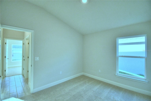 spare room with light carpet and vaulted ceiling