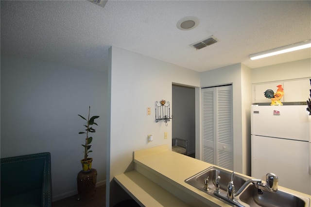 kitchen featuring sink, white refrigerator, and a textured ceiling