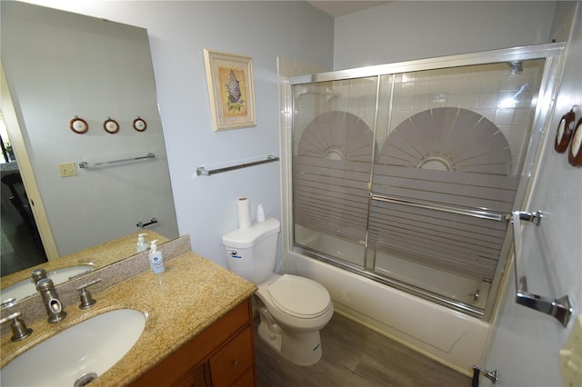 full bathroom with toilet, vanity, bath / shower combo with glass door, and hardwood / wood-style floors