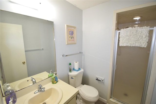 bathroom featuring a shower with door, vanity, and toilet