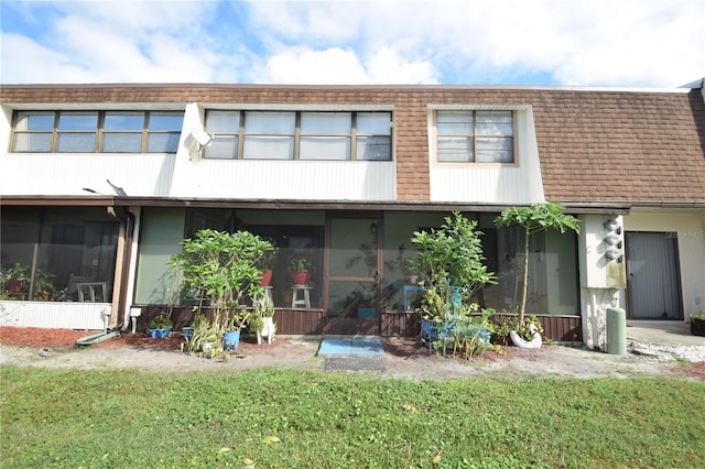 rear view of property featuring a sunroom and a yard