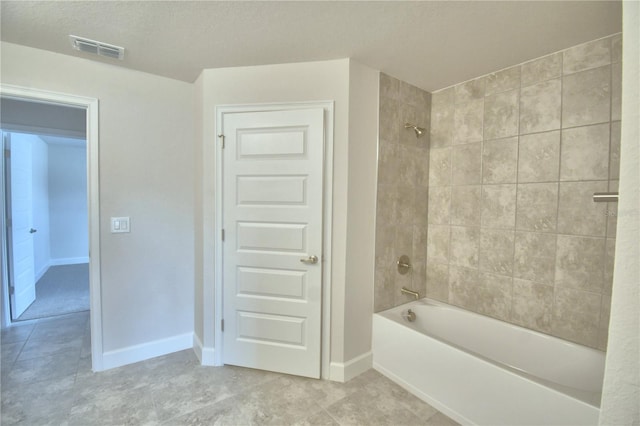 bathroom featuring a textured ceiling, tile patterned floors, and tiled shower / bath combo