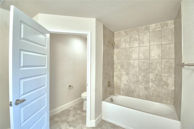 bathroom featuring toilet, tiled shower / bath combo, a textured ceiling, and tile patterned flooring