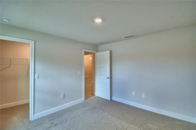 unfurnished bedroom with carpet flooring, a spacious closet, and a closet