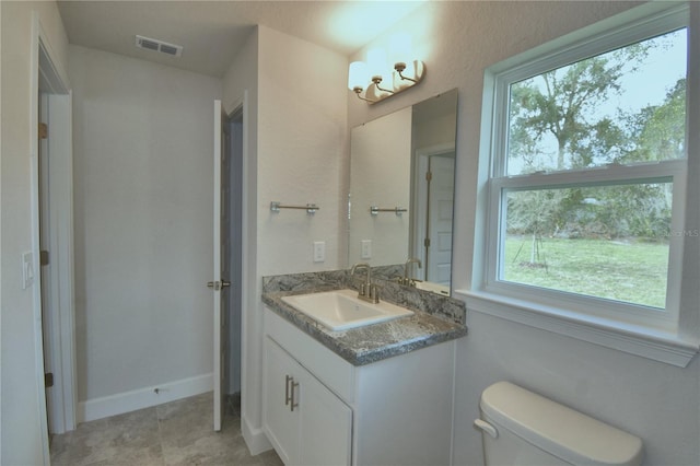 bathroom with toilet, vanity, and a healthy amount of sunlight