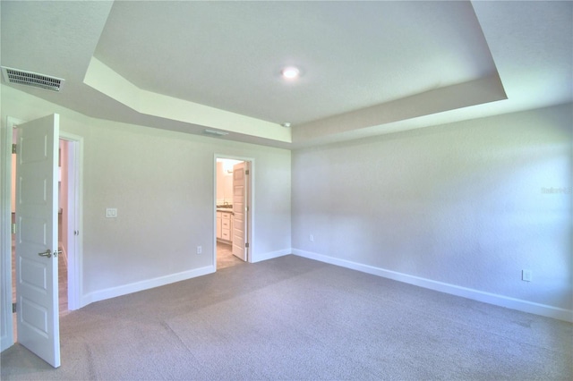 unfurnished room with carpet floors and a tray ceiling