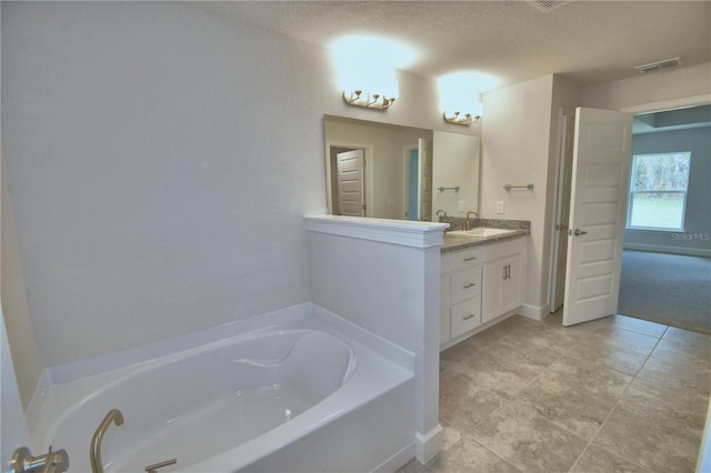 bathroom with vanity, a textured ceiling, and a tub