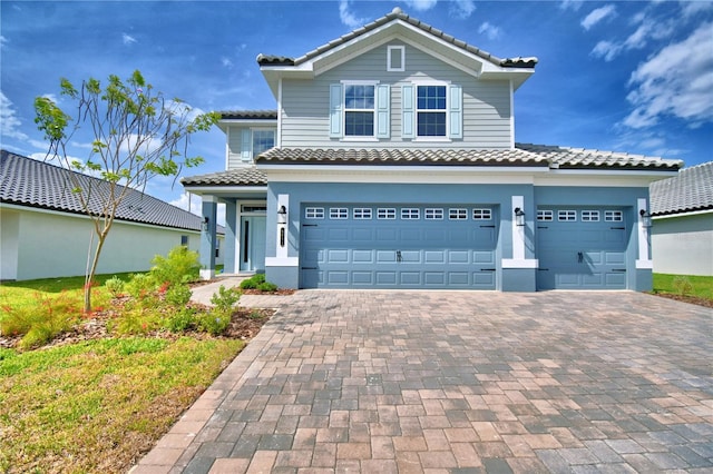 view of front facade featuring a tiled roof, a garage, and decorative driveway