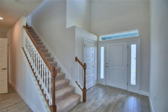 foyer with stairs, light wood finished floors, a high ceiling, and baseboards