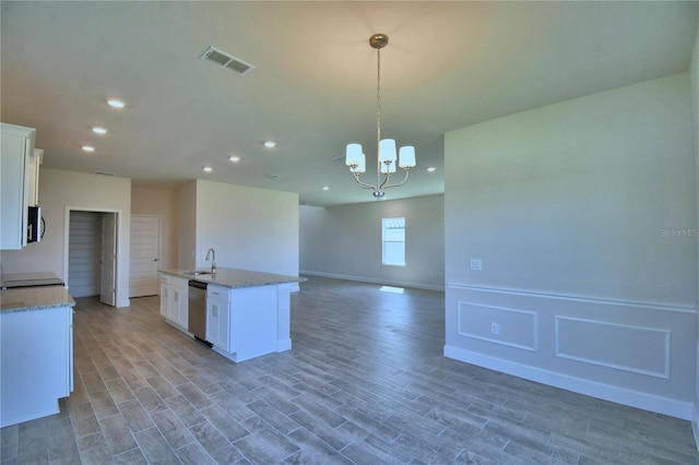 kitchen featuring a kitchen island with sink, light wood-style floors, stainless steel dishwasher, and an inviting chandelier