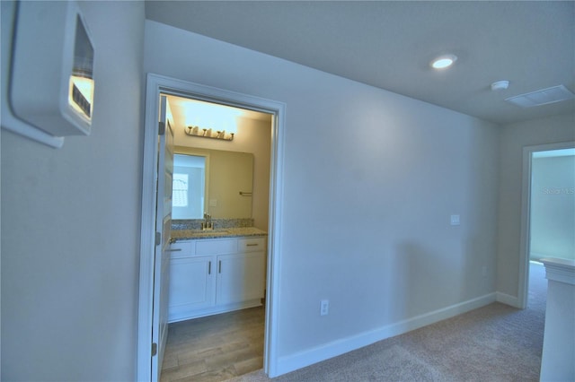 interior space featuring a sink, light colored carpet, and baseboards