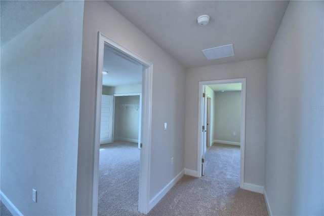 hallway with carpet flooring, visible vents, and baseboards