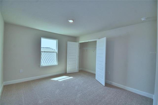 unfurnished bedroom with a closet, baseboards, and carpet