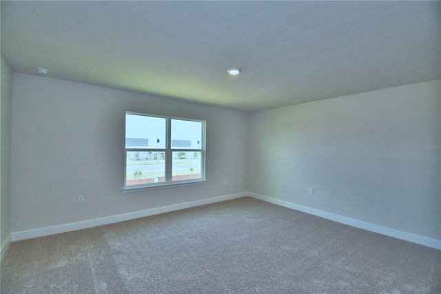 spare room featuring carpet floors and baseboards