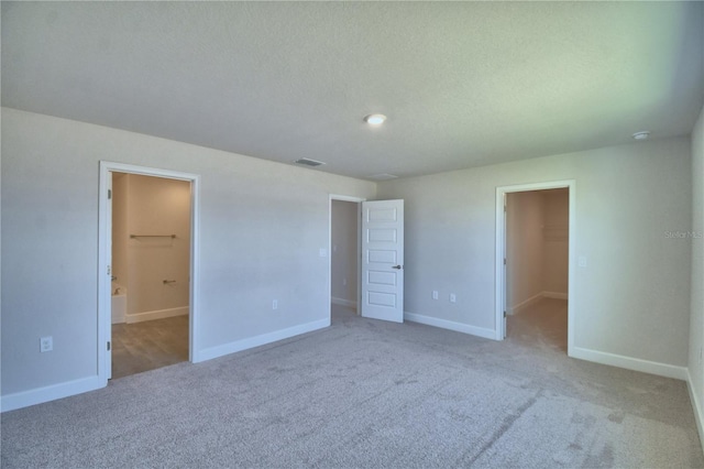 unfurnished bedroom with a spacious closet, carpet, visible vents, and baseboards