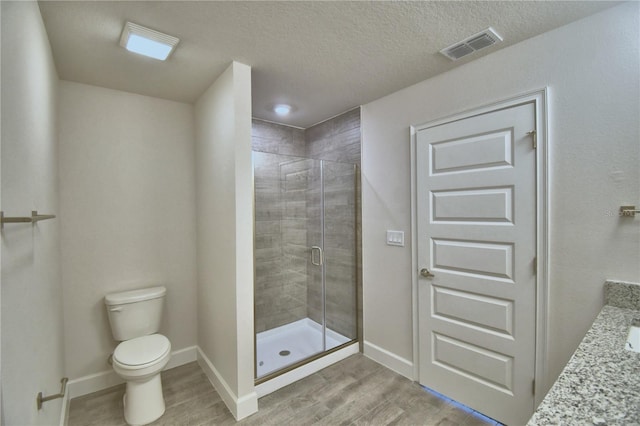 full bath with toilet, a shower stall, wood finished floors, and baseboards