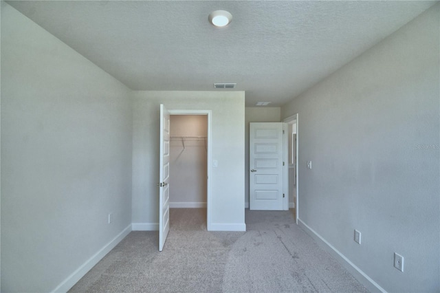 unfurnished bedroom with a closet, baseboards, a textured ceiling, visible vents, and light colored carpet