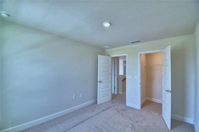 unfurnished bedroom featuring visible vents, baseboards, a closet, a textured ceiling, and carpet floors