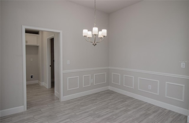 empty room with a chandelier and light hardwood / wood-style flooring