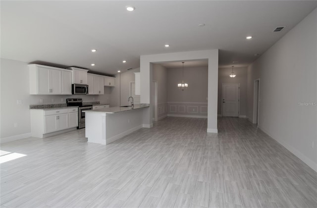 kitchen featuring stainless steel appliances, white cabinets, kitchen peninsula, sink, and light wood-type flooring