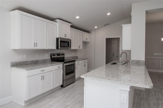 kitchen with kitchen peninsula, white cabinets, sink, and appliances with stainless steel finishes