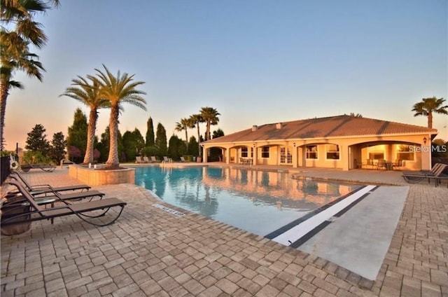 pool at dusk featuring a patio area