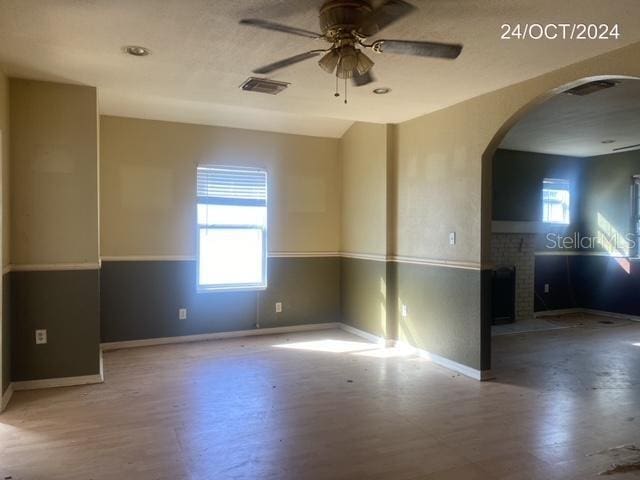 empty room with ceiling fan, a fireplace, and wood-type flooring