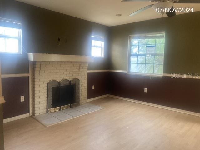 unfurnished living room featuring ceiling fan, a fireplace, and light wood-type flooring