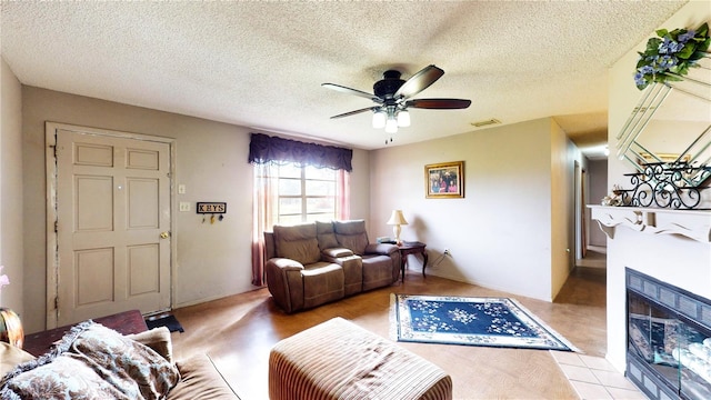 living room featuring a fireplace, ceiling fan, and a textured ceiling